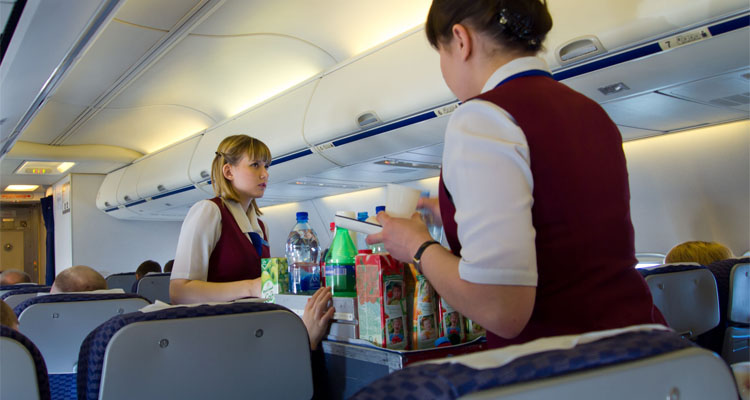 Stewardessen, die einen Catering-Trolley handhaben
